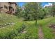 A peaceful backyard featuring a small creek, lush greenery, and a split rail fence at 27756 Troublesome Gulch Rd, Evergreen, CO 80439