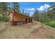 Exterior of a barn featuring a red and tan exterior with an open stalls and surrounded by a dirt paddock at 27756 Troublesome Gulch Rd, Evergreen, CO 80439