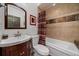 Cozy bathroom with vanity, toilet, tub with shower and decorative earth-toned tile at 27756 Troublesome Gulch Rd, Evergreen, CO 80439