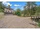 Exterior view of a home featuring a three car garage, long driveway and a creek with a wooden bridge at 27756 Troublesome Gulch Rd, Evergreen, CO 80439