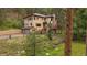 Exterior of a two-story home featuring a spacious deck and serene landscaping at 27756 Troublesome Gulch Rd, Evergreen, CO 80439