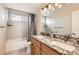 Bathroom featuring dual sinks, granite countertops, and a tub/shower combination with tile surround at 7411 S Curtice Ct, Littleton, CO 80120