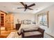 Well-lit bedroom with wood floors, a ceiling fan, closet, and a cozy seating area next to a window at 7411 S Curtice Ct, Littleton, CO 80120