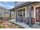Inviting covered front porch with comfortable seating and stylish brick accents at 7411 S Curtice Ct, Littleton, CO 80120