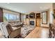 A cozy living room featuring hardwood floors, a fireplace, and large windows with outdoor views at 7411 S Curtice Ct, Littleton, CO 80120