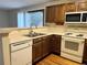 Well-lit kitchen with wood cabinets, white appliances, and a sink with a view to the outside at 17969 E Brown Pl, Aurora, CO 80013