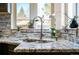 Close-up of a kitchen sink featuring granite countertops, mosaic backsplash, and a stainless steel faucet at 2855 Albion St, Denver, CO 80207