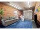 Finished garage space with exposed brick, plush blue carpet, and comfortable seating arrangement at 2855 Albion St, Denver, CO 80207