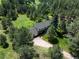 Aerial shot of a home surrounded by dense trees, featuring a long driveway and sprawling landscape at 11824 E Basswood Ln, Franktown, CO 80116