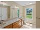 The bathroom includes a double vanity, and a shower with views of the lush backyard at 11824 E Basswood Ln, Franktown, CO 80116