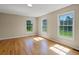 A sun-filled bedroom boasts gleaming hardwood floors and multiple windows with views of the lush outdoors at 11824 E Basswood Ln, Franktown, CO 80116