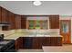 A view of the kitchen showcasing dark wood cabinets, a window, tile backsplash, an oven, and an adjacent wooden door at 11824 E Basswood Ln, Franktown, CO 80116