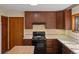 An image of the kitchen featuring wooden cabinets, cream countertops, a black oven, a door, and tile backsplash at 11824 E Basswood Ln, Franktown, CO 80116
