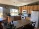 Efficient kitchen features warm wood cabinets, white appliances, and a center island with seating at 1998 E 100Th Pl, Thornton, CO 80229