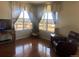 Living room area with hardwood flooring features a comfortable recliner, side table, and large windows at 1998 E 100Th Pl, Thornton, CO 80229