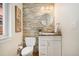 Powder room featuring stone accent wall, modern vanity, round mirror, and contemporary fixtures at 1551 S Grant St, Denver, CO 80210