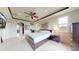 Spacious bedroom featuring a tray ceiling, fan, large bed, and ensuite bathroom access at 16491 Fairway Dr, Commerce City, CO 80022