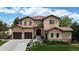 Charming two-story home features a terracotta roof, stone accents, a three-car garage, and a beautifully landscaped front yard at 16491 Fairway Dr, Commerce City, CO 80022