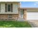 Home exterior featuring a well-kept lawn, brick facade accents, and a clean, white garage door at 11199 Dahlia Pl, Thornton, CO 80233