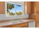 Close up of double sink under window, oak cabinets and white dishwasher at 11199 Dahlia Pl, Thornton, CO 80233