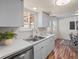 Bright kitchen with stainless steel appliances, a double basin sink, white cabinetry, and wood-look floors at 10415 Owens Cir, Broomfield, CO 80021