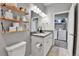 Well-lit bathroom with double sinks, floating shelves, and a view into the laundry room at 11250 Florence St # 21A, Commerce City, CO 80640