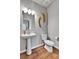Stylish half bathroom featuring a pedestal sink, toilet, modern lighting, and decorative gold wall art at 11250 Florence St # 21A, Commerce City, CO 80640