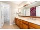 Well-lit bathroom with a double sink vanity, framed mirror, and an adjacent shower/tub combo at 2480 W Jamison Way, Littleton, CO 80120