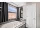 Luxurious bathtub area featuring elegant tile work, a frosted window, and modern fixtures at 9195 Anasazi Indian Trl, Highlands Ranch, CO 80129