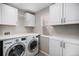 Well-organized laundry room equipped with modern washer, dryer, ample counter space, and storage cabinets at 9195 Anasazi Indian Trl, Highlands Ranch, CO 80129
