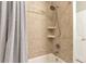 Shower stall featuring tan tiles, shelving, and a chrome showerhead and handle at 7426 Blue Water Ln, Castle Rock, CO 80108