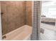 Bathroom featuring a tiled bathtub, accented with a black and white shower curtain, and views of the bedroom at 17046 Desert Wine Trl, Parker, CO 80134