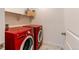 Bright laundry room featuring a modern, red front load washer and dryer set with white shelving for storage at 17046 Desert Wine Trl, Parker, CO 80134