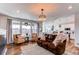 Inviting living room with a brown leather sofa, large windows, and open concept to the kitchen at 17046 Desert Wine Trl, Parker, CO 80134