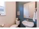 Modern powder room features a pedestal sink, toilet, stylish mirror, and blue accent wall at 17046 Desert Wine Trl, Parker, CO 80134