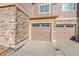 Attached garages with neutral doors, stone and siding exterior, close up view on a sunny day at 5660 S Algonquian Way # A, Aurora, CO 80016