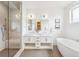 Bright bathroom featuring double vanity, tub, and glass shower with bench at 6854 Carr St, Arvada, CO 80004