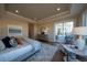 Main bedroom featuring neutral decor, tray ceiling, sitting area, and access to outdoor patio at 367 Josef Cir, Fort Lupton, CO 80621