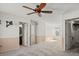 Spacious carpeted bedroom with a ceiling fan, white walls, and a doorway to the ensuite bathroom at 8731 Wildrye Cir, Parker, CO 80134