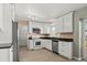 White kitchen with stainless steel appliances, light wood flooring, and ample counter space at 8731 Wildrye Cir, Parker, CO 80134