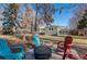 Backyard with colorful Adirondack chairs around a fire pit and a well-maintained lawn at 1351 Reed St, Lakewood, CO 80214