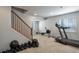 Basement workout area with treadmill, rowing machine, dumbbells, and wood stairs at 8915 Edgewood Ln, Highlands Ranch, CO 80130