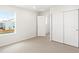 Bright bedroom features a window with blinds and a closet with paneled doors and neutral carpet at 571 Homestead Ave, Brighton, CO 80601