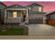Charming two-story home with a covered porch, stone accents, and a two-car garage at sunset at 571 Homestead Ave, Brighton, CO 80601