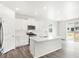 Eat-in kitchen boasts wood-look floors, white cabinetry, stainless appliances, and island seating at 571 Homestead Ave, Brighton, CO 80601
