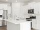 Bright kitchen features stainless appliances, white cabinetry, and a center island with sink at 571 Homestead Ave, Brighton, CO 80601