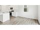 Eat-in kitchen boasts wood-look floors, white cabinetry, stainless appliances, and bright lighting at 571 Homestead Ave, Brighton, CO 80601