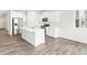 Eat-in kitchen boasts wood-look floors, white cabinetry, stainless appliances, and island seating at 571 Homestead Ave, Brighton, CO 80601