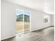 Bright, empty living room features wood-look flooring and sliding glass door to the backyard at 571 Homestead Ave, Brighton, CO 80601