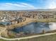 Aerial view of a community pond surrounded by houses and green spaces with distant mountains at 12431 Red Fox Way, Broomfield, CO 80021